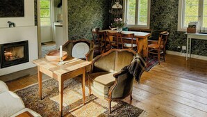 Une pièce chaleureuse avec une cheminée, une table à manger avec des chaises et une grande fenêtre.