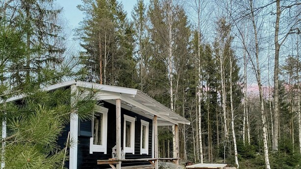 Une cabane dotée d’une terrasse en bois, d’une table et de bancs.