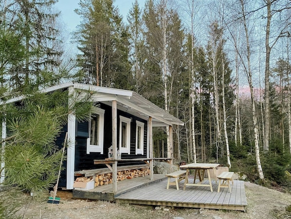 A cabin with a wooden deck, a table, and benches. - Historic 19th century cottage in Blekinge (Kyrkhult)
