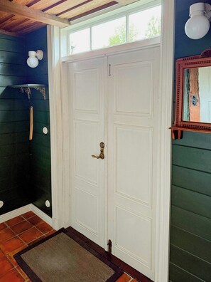 A white double door with a brass handle, a wooden ceiling, and a small window above. - Historic 19th century cottage in Blekinge (Kyrkhult)