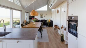 A modern kitchen with a large island, white cabinetry, and a view of the outdoors. - Fresh air on open terrace with view (Hejls)