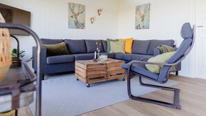 A living room with a sofa, a coffee table, and a chair. - Fresh air on open terrace with view (Hejls)