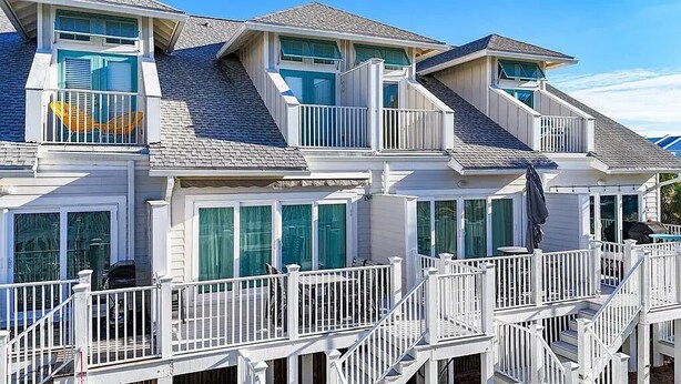A multi-story building with balconies, large windows, and a covered outdoor area. - Saltlife - Beachside Townhome - Pool - Just Steps from Beach (Mexico Beach)