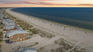 A coastal area with a beach, a row of houses, and a clear sky. - Saltlife - Beachside Townhome - Pool - Just Steps from Beach (Mexico Beach)