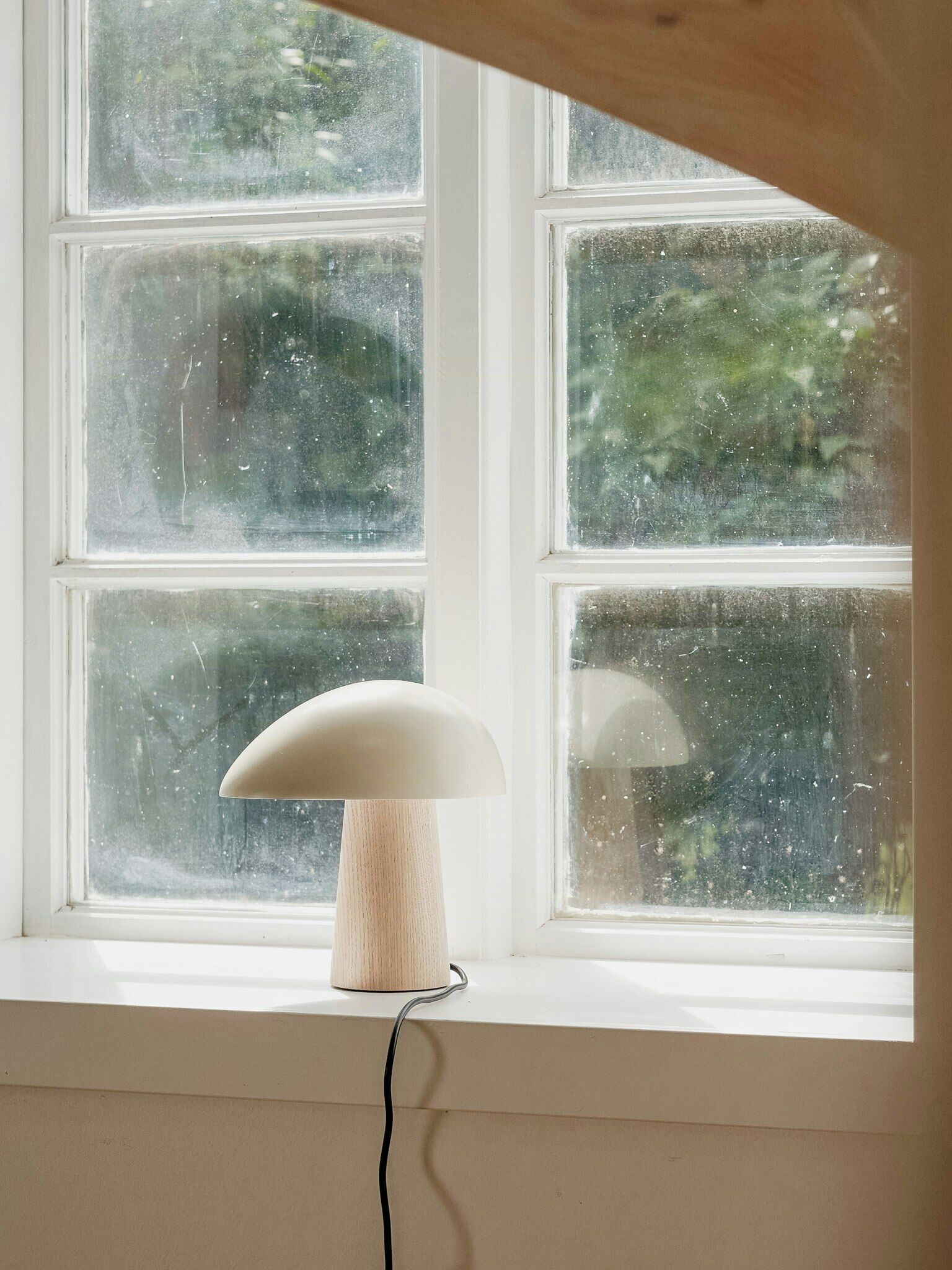 Een lamp op een vensterbank met uitzicht op een raam met meerdere ruiten.