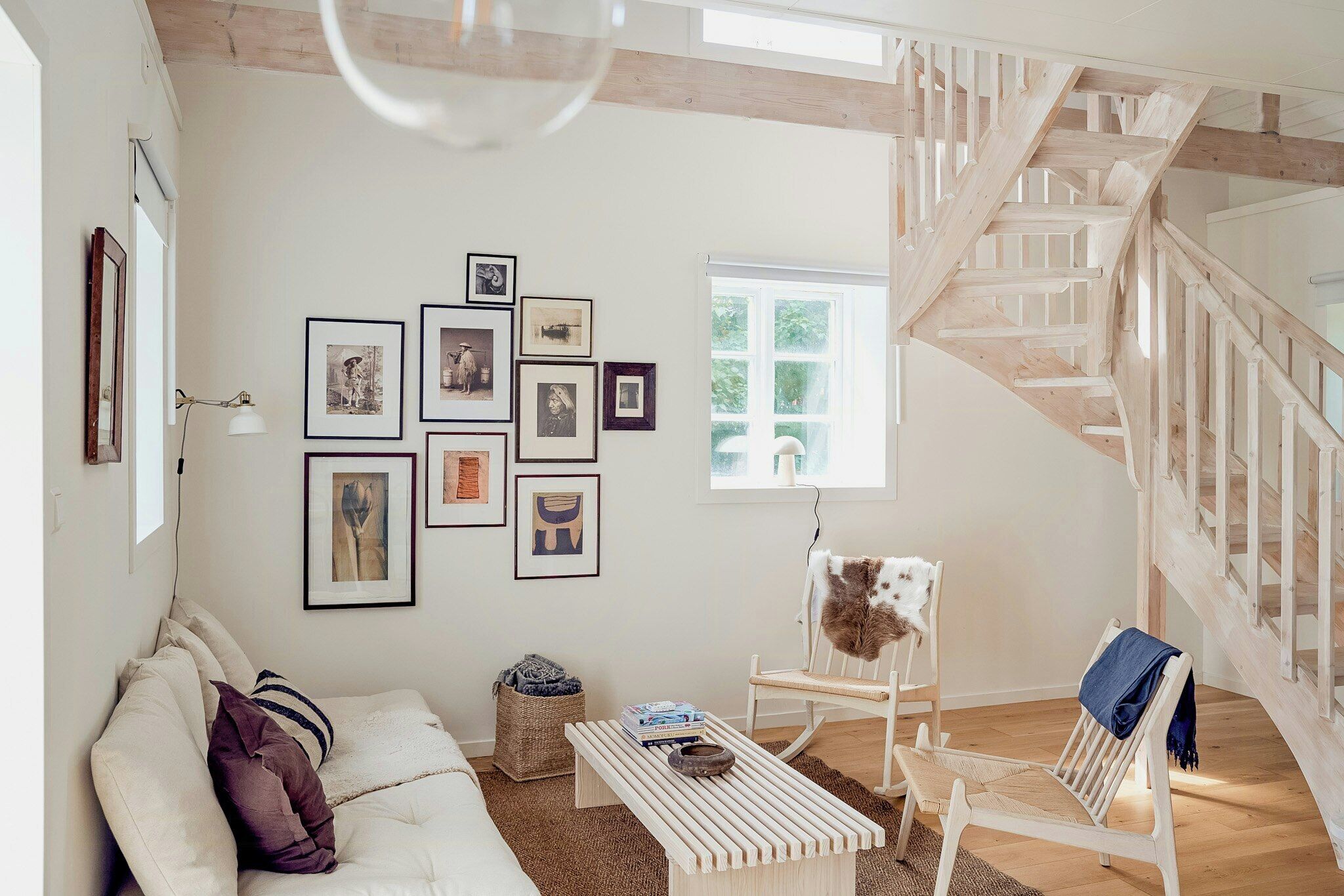 Un vaste espace de vie comprenant un canapé blanc, une table basse en bois et un escalier.