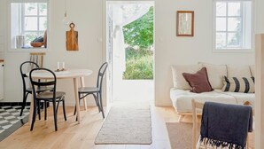 A room with a dining table, chairs, a sofa, and a view of greenery outside. - Charming Hen House with Terrace near Vadstena (Vadstena)