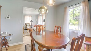 A dining area with a round wooden table, chairs, pendant lights, and a view of a living room. - Renovated Birmingham Cottage: Great Outdoor Space! (Birmingham)