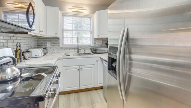 A modern kitchen with white cabinetry, stainless steel appliances, and a window providing natural light. - Renovated Birmingham Cottage: Great Outdoor Space! (Birmingham)