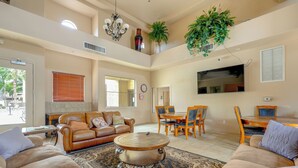 A spacious living area with a high ceiling, a dining table with chairs, a large flat-screen TV, and a coffee table. - Resort-style Pools & Hot Tubs! Mtn-view Mesa Condo (Mesa)