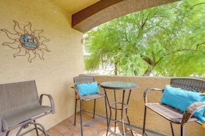 A patio with wicker furniture, a welcome sign, and a view of green trees.