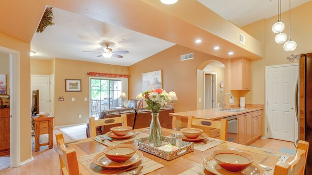A dining area with a wooden table set for four, a vase with flowers, and a ceiling fan. - Resort-style Pools & Hot Tubs! Mtn-view Mesa Condo (Mesa)