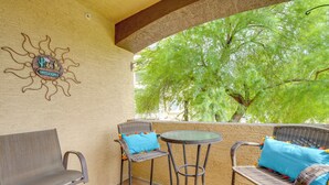 A patio with wicker furniture, a welcome sign, and a view of green trees. - Resort-style Pools & Hot Tubs! Mtn-view Mesa Condo (Mesa)