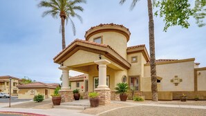 A building with a curved facade, a central entrance with a porch, and multiple potted plants. - Resort-style Pools & Hot Tubs! Mtn-view Mesa Condo (Mesa)
