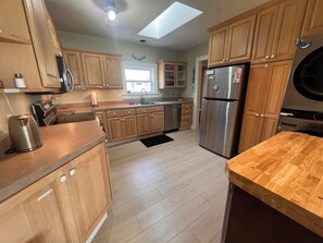 A modern kitchen with wooden cabinets, stainless steel appliances, and a skylight. - Ocean Perch – Walk to the Beach, Prom and Golf | Family-Friendly Seaside Retreat (Seaside)