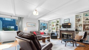 A living room with leather chairs, a fireplace, a television, and a bookshelf. - Sand Dollar at Seaside Beach (Seaside)