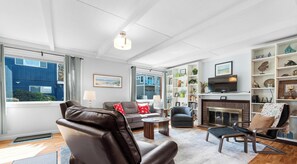 A living room with leather chairs, a fireplace, a television, and a bookshelf. - Sand Dollar at Seaside Beach (Seaside)