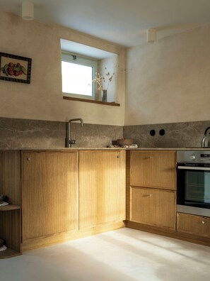 Eine Küche mit Holzausstattung, einem eingebauten Ofen und einem Fenster über der Spüle.