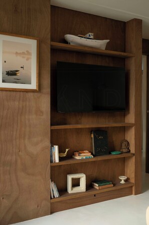 Eine Holzwand mit einem gerahmten Bild, einem Fernseher und Regalen mit Büchern und Dekoration.