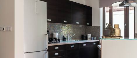 A modern kitchen with dark cabinets, a tiled backsplash, and a coffee bar.