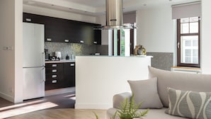 A modern kitchen with dark cabinets, a central island, and a stainless steel range hood. - Sopot Haffnera - close to the beach  (Sopot)