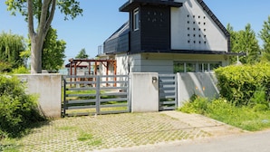 Ett modernt hus i två våningar med garage, en grind vid infarten och en asfalterad uppfart.