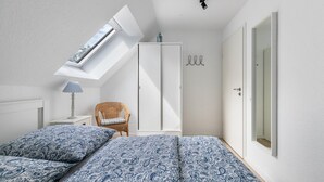 A bedroom with a skylight, a wardrobe, a chair, and a bed with patterned bedding. - NEW - Artist’s Retreat Halebüll with Sea View, Shared Terrace and Wi-Fi (Husum)