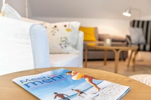 A magazine on a table with a sofa and a lamp in the background.