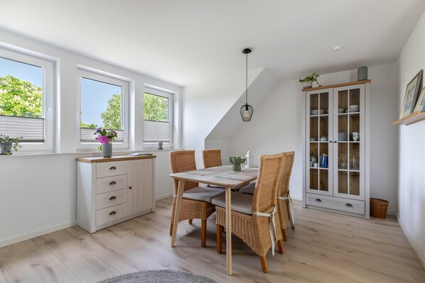 A modern kitchen with a dining table, chairs, and a cabinet.