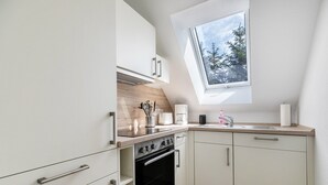 A modern kitchen with white cabinets, a black oven, a skylight, and a window overlooking trees. - NEW - Artist’s Retreat Halebüll with Sea View, Shared Terrace and Wi-Fi (Husum)