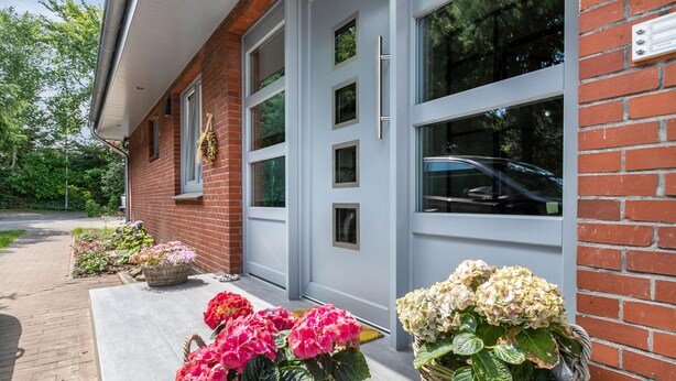 A building with a brick facade, large windows, and a paved entrance area with potted plants. - Modern Coastal Retreat – Newly Renovated with Partial Sea View, Shared Garden & Wi-Fi (Husum)