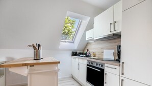 A modern kitchen with a skylight, white cabinets, and a wooden countertop. - Modern Coastal Retreat – Newly Renovated with Partial Sea View, Shared Garden & Wi-Fi (Husum)