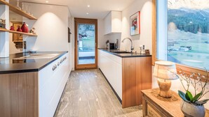 Een moderne keuken met een centraal eiland, een houten kast en uitzicht op een bergachtig landschap.