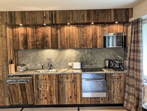 A kitchen with wooden cabinetry, a stainless steel sink, a toaster, a coffee maker, and an oven.