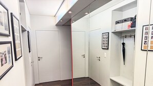 Een gang met witte deuren, ingelijste foto's aan de muur en een houten vloer.
