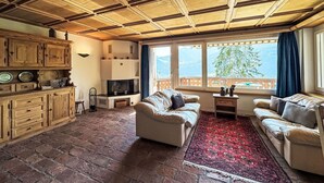 A living room with a fireplace, sofas, a TV, and a view of the outdoors.