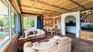 A cozy living room with a wooden ceiling, a sofa, a dining table, and a kitchen area.