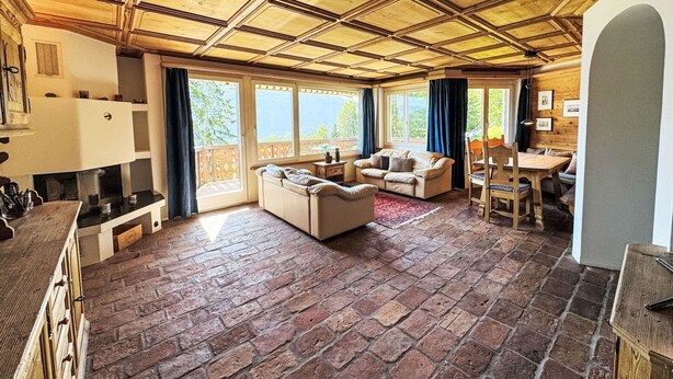 A spacious living area with a fireplace, a sofa, a dining table, and a view of the outdoors.