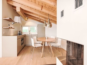 Eine moderne Küche mit Essbereich, Holzbalkendecke, weißen Schränken und Pendelleuchten.