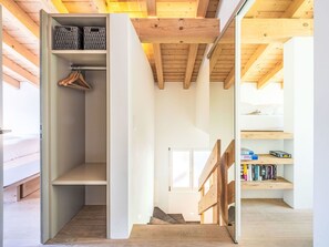 Ein modernes Interieur mit Holzboden, einem Einbauschrank mit Kleiderstange, einer Treppe und einem Bücherregal.