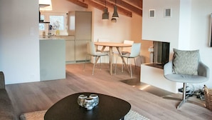 Un soggiorno moderno con un tavolino rotondo, un'area pranzo con tavolo e sedie, e una cucina sullo sfondo.