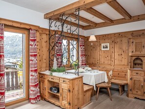 Ein Holzblockhaus-Interieur mit Essbereich, Spüle und Radio, mit Blick auf einen verschneiten Berg.