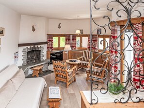 Ein gemütliches Wohnzimmer mit Kamin, Holzmöbeln und Blick ins Freie.