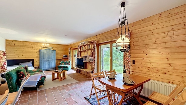 L’intérieur d’un chalet en bois comprend un coin repas, un canapé, un téléviseur et une bibliothèque.