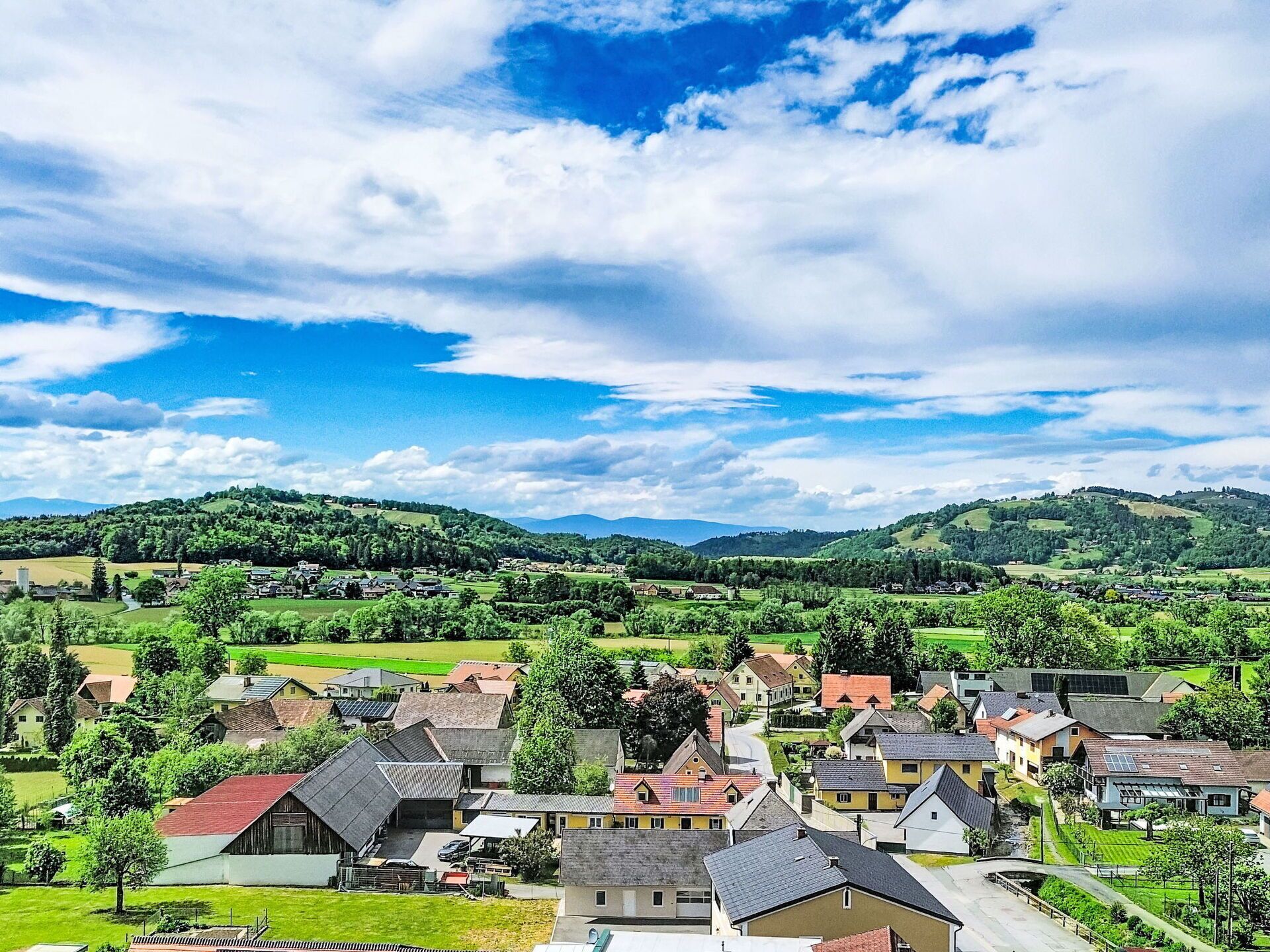 Un pueblo rural con casas, campos verdes y colinas al fondo.