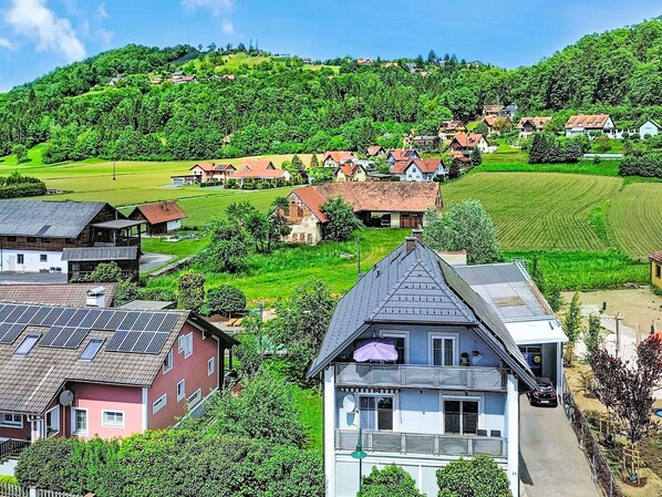 Ein Wohngebiet mit Häusern, einem markanten Gebäude mit Satteldach und einer grünen Landschaft.