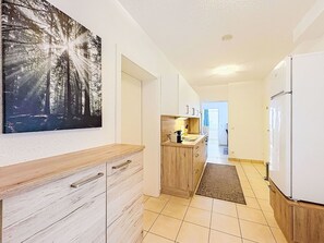 Ein schmaler Flur mit Küchenzeile, die ein Holzboden, Schränke und einen Kühlschrank umfasst.