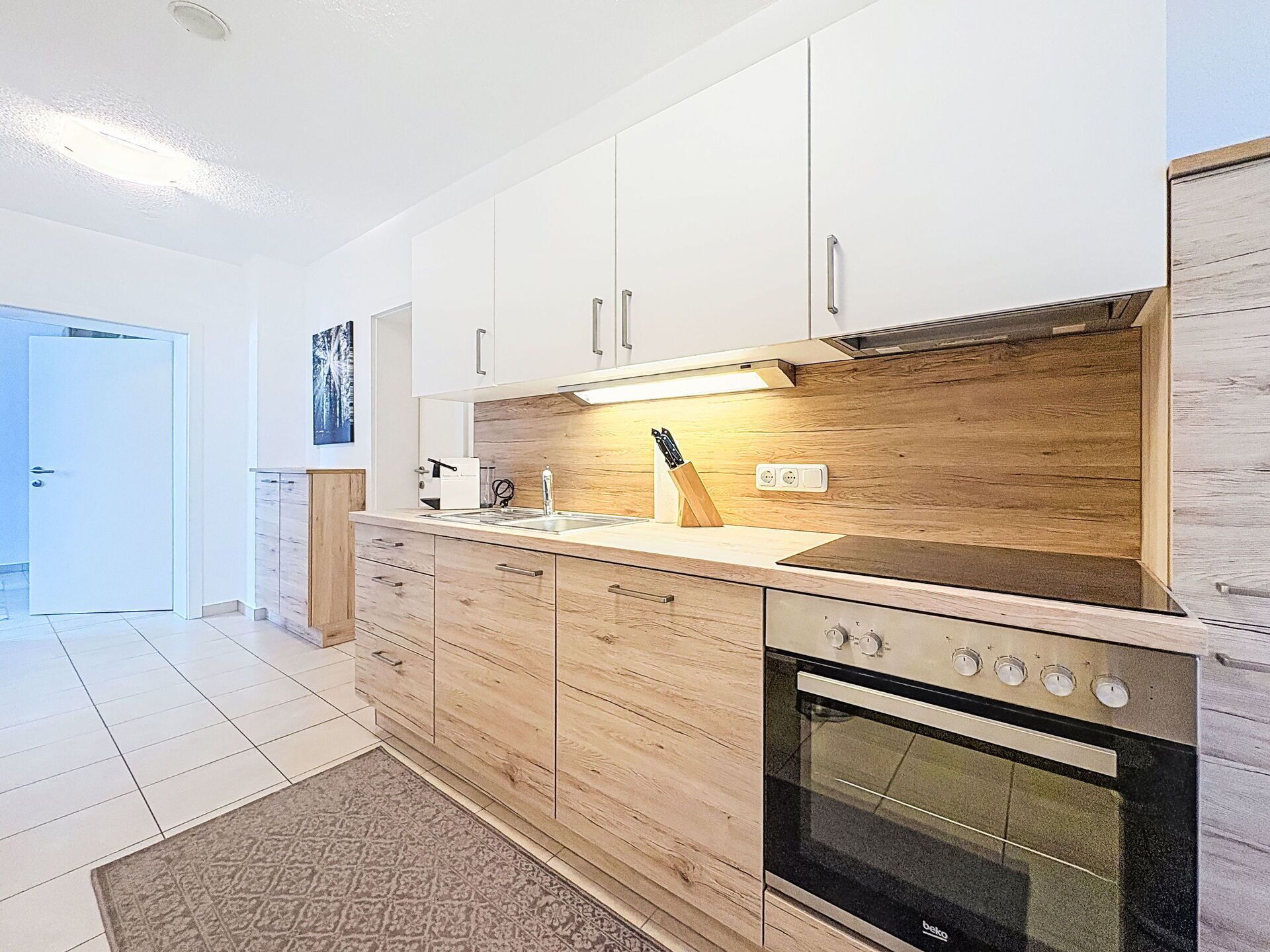 A modern kitchen with wooden cabinets, a built-in oven, and a countertop with a knife block.