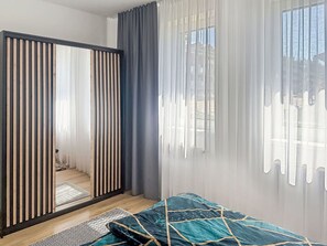 Une chambre Ă coucher avec un lit, une porte coulissante, une fenĂȘtre avec des rideaux et une vue sur lâextĂ©rieur.