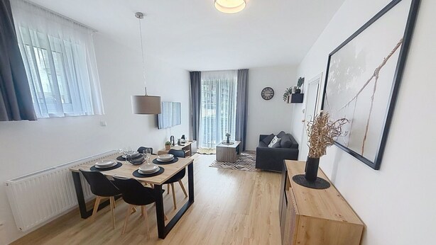A modern living room with a dining area, a sofa, a coffee table, and a painting on the wall.